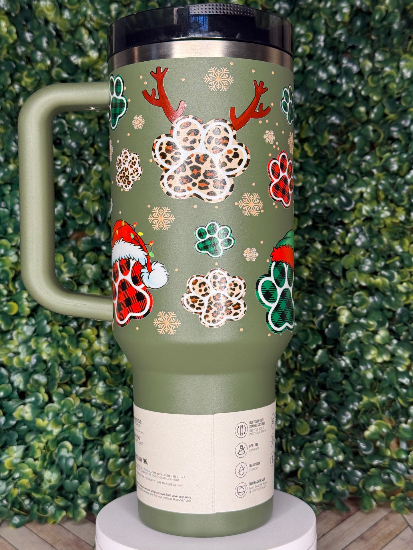 A green insulated thermos mug with a leopard print design and snowflakes decorating the exterior.